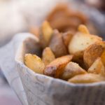 Delicious golden potato wedges in a paper cone, perfect for a snack or appetizer.