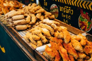 Delicious assortment of crispy fried food skewers displayed at a vibrant Thai street market.